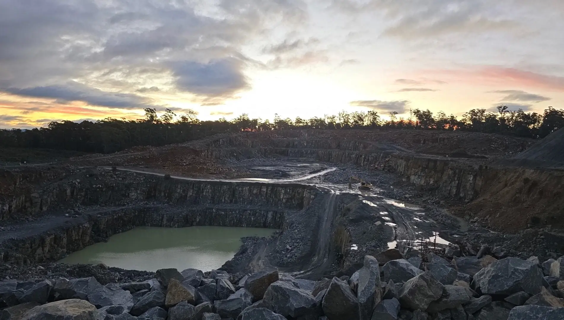 Benched quarry and haul roads across a Tasmanian site at dusk